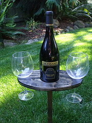  Brown Jordan Outdoor Furniture, small patio table with bottle of wine and two glasses on grass.
