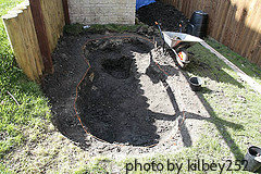 Dugout pond hole with red rope marking and frost hole dug in middle, digging a backyard pond, pond construction