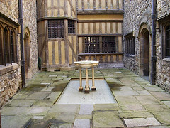 Water fountain basin sitting in the middle of castle courtyard with stone and wood walls, stone water fountains, indoor water fountains.