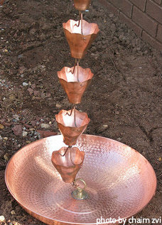 Hammered copper rain chain decorative basin on ground with copper rain chain cups hanging with clips, decorative copper rain chain, unique rain chain basin.
