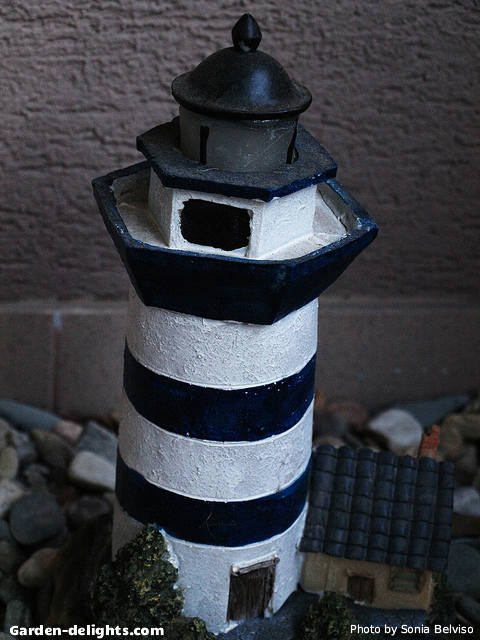  Miniature solar garden lighthouse with black and white stripes in a rock bed garden, solar garden light, outdoor lighthouse kits, Walmart, wooden lighthouses.