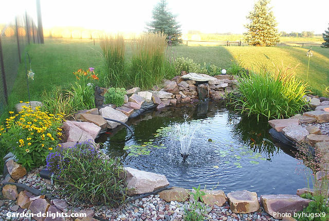  Garden water feature on corner of acreage surrounded by a rock boulder outline with a water fountain spray feature in the middle with marginal colorful plants and water lilies floating in the water, how to build a large pond, easy backyard pond, backyard pond kits, Walmart water fountains, garden ponds, pond circular Water stones, ponds with fountain spray, garden water art, small pond fountains. Even when on and acreage you can have a small to medium size water pond feature that will add an interesting design idea.