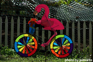 Pink flamingo wind spinner riding bike with colorful wheels, garden wind spinners, wind art.