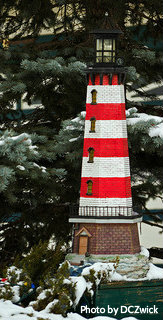 Red and white striped lighthouse with replica stone on bottom and black beacon with light, garden lighthouses, replica lawn lighthouses.