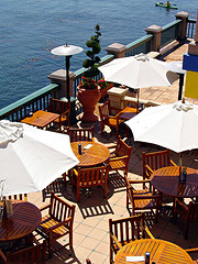 Teak Garden Furniture, teak outdoor furniture sets on restaurant balcony with patio heaters overlooking water.