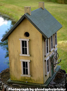Two-story birdhouse with green roof and to chimney stacks, wood birdhouse, homemade wooden birdhouse.