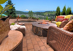 modern outdoor furniture, two Wicker loveseat with colorful pillows sitting on a stone fireplace overlooking green valley.