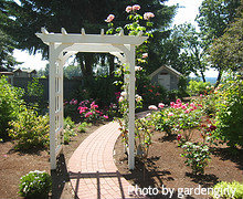 White wooden arbor with red brick pathway flowing through in Rose Garden, outdoor garden arbors, wooden garden arbor.