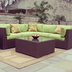  Wholesale Outdoor Furniture, Wicker sectional with lime green patio cushions and Wicker table with oranges in bowl.