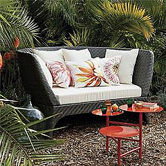 Outdoor furniture replacement cushions, wicker sofa with white pillow cushions and red table.