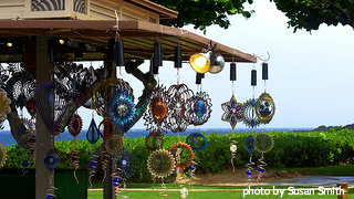 wind spinners hanging from kiosks roof by the beach, wind spinners, wind sculptures.