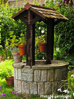 Stone finish wishing well with dark wood cedar shingles with small flowerpots, rustic wishing well,decorative wishing wells.