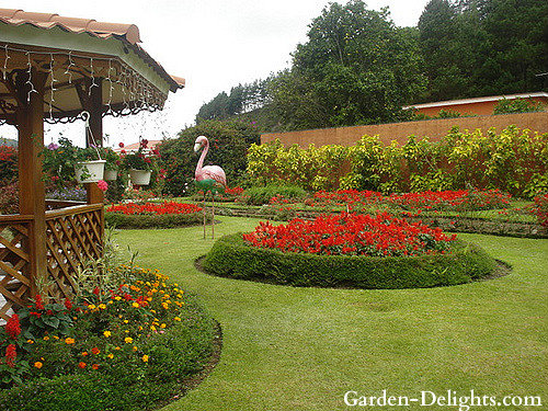 Red flowers in circular garden bed with gazebo, planting perennials, planting annuals, choosing plants for the garden.