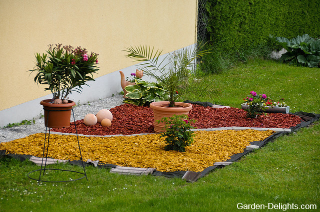 Yellow and red mulch in flower bed with flower pots, mulching control weeds, mulch for garden, organic mulch, choose right mulch, simple flower beds.